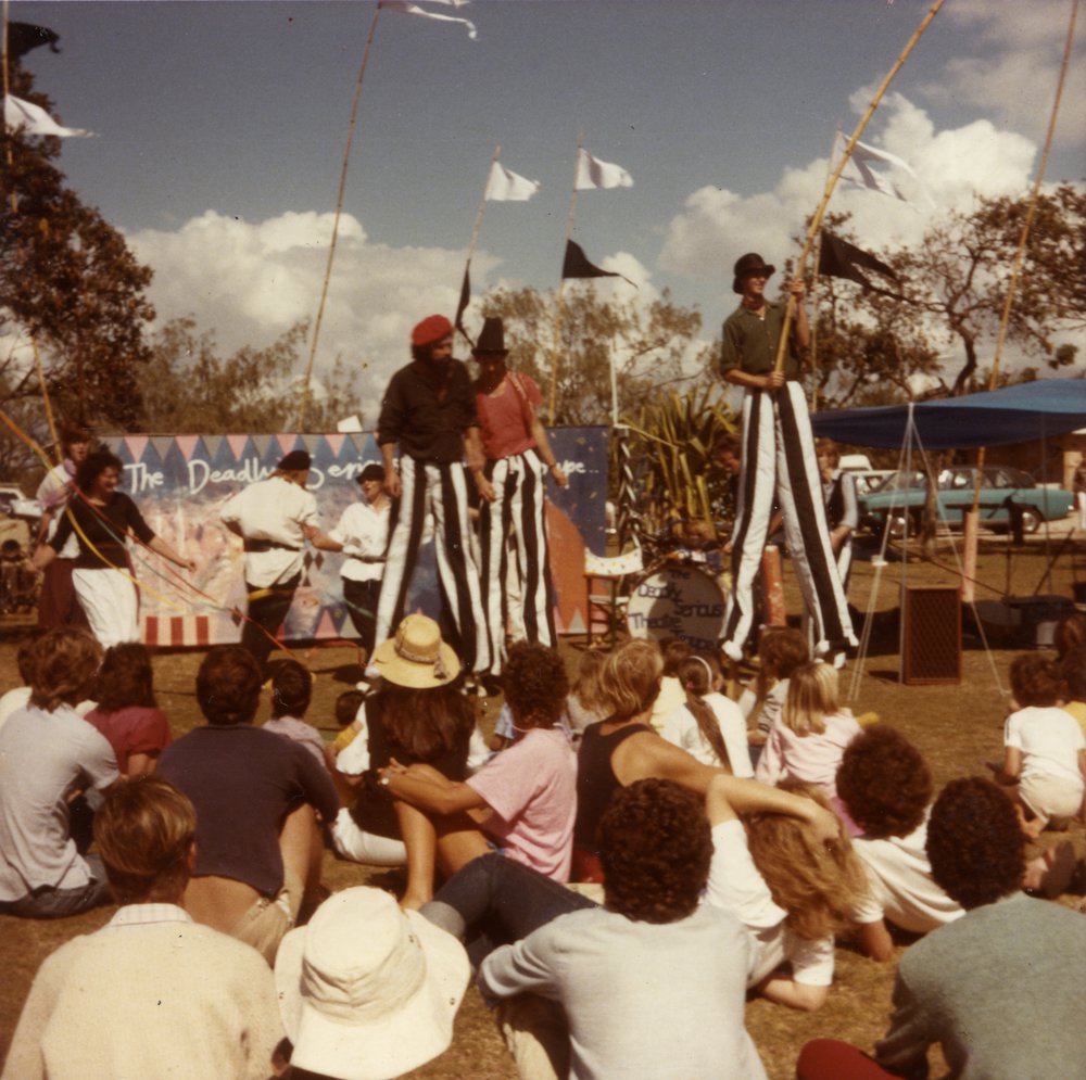 David Ashton (centre), stilt walking with 'The Deadly Serious Theatre Troupe', Peregian Beach, 1980s