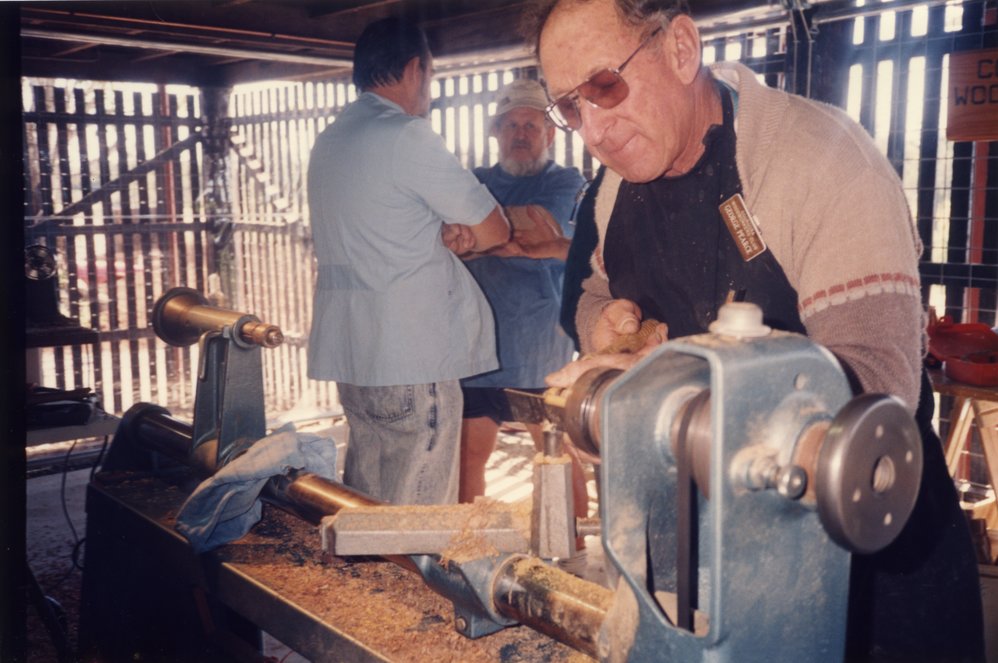 George Pearce, Cooroora Woodworkers, demonstrates wood turning under Wallace House, Wallace Park, Noosaville, 1993